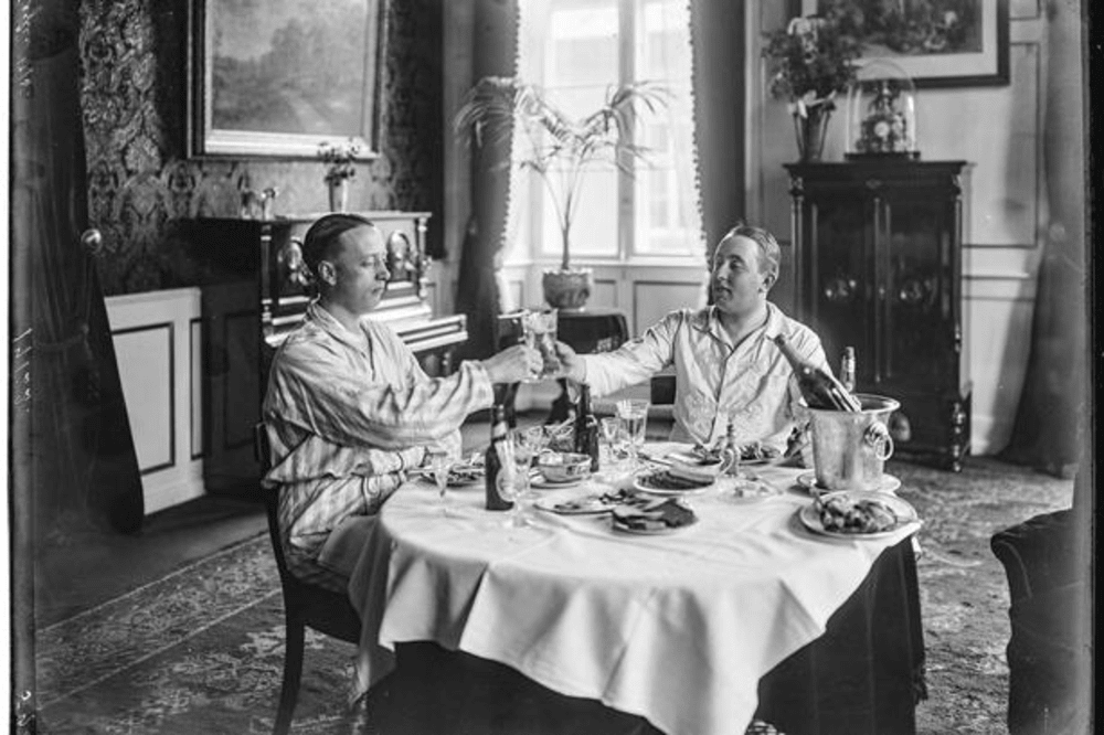 Aktiespekulanten Olaf Bigler i silkepyjamas med silkesnore og perlemorsknapper sammen med vennen Kaj Folkenberg på Hotel Phønix i 1918. Ved samme lejlighed tog de vist også en tur i hotellets lysekroner. .Foto: Peter Elfelt/Det Kongelige Bibliotek